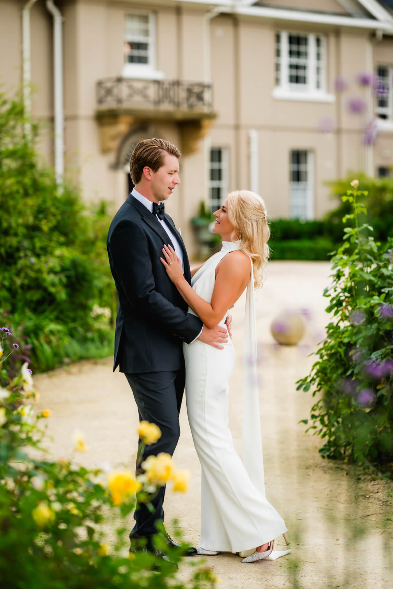 Elegant couple embracing in garden setting.