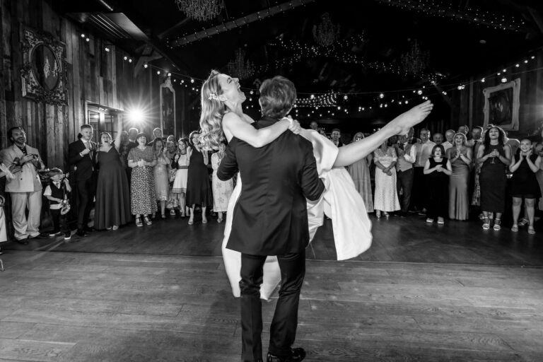 Bride lifted during joyful wedding dance celebration.