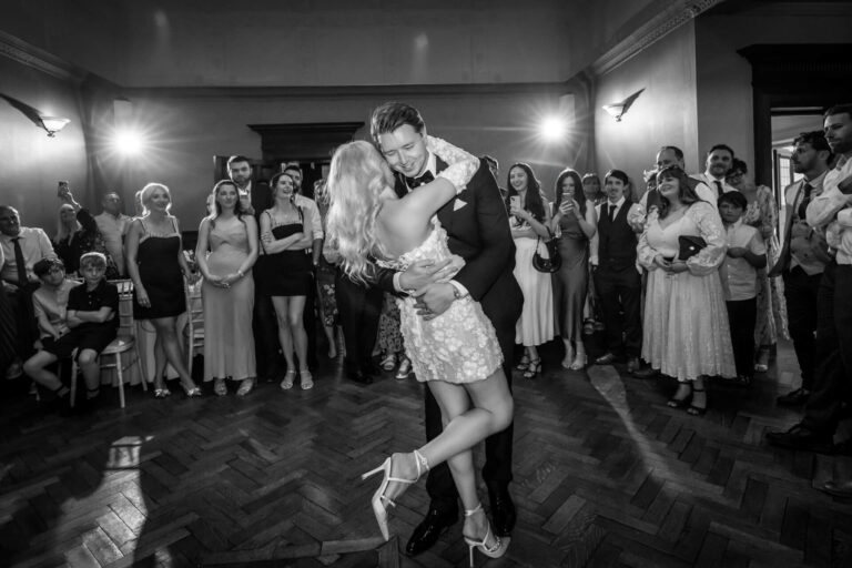 Couple dancing at wedding surrounded by guests.