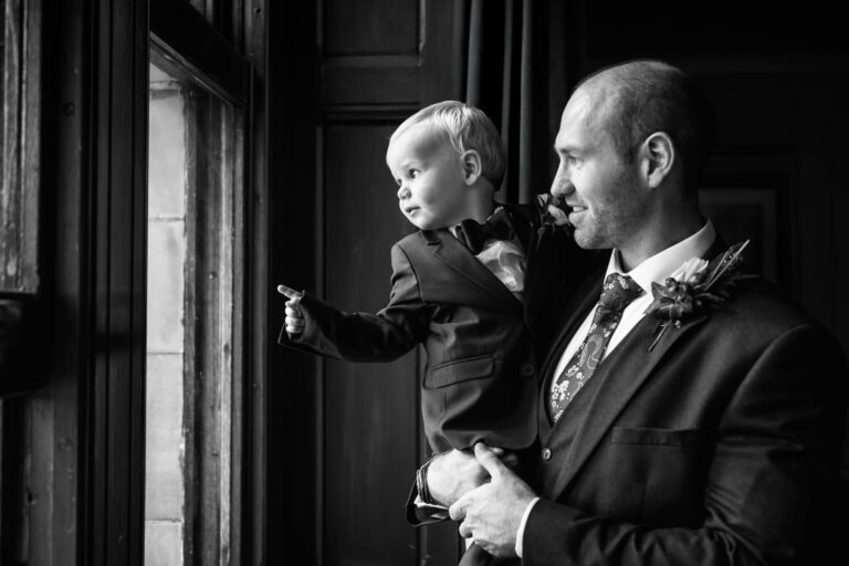 Man and child looking out window in suits