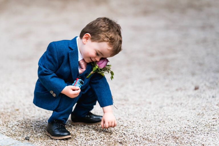 Child in blue suit playing with toy car.