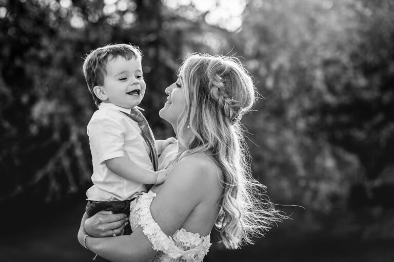 Woman holding smiling child outdoors, black and white photo.