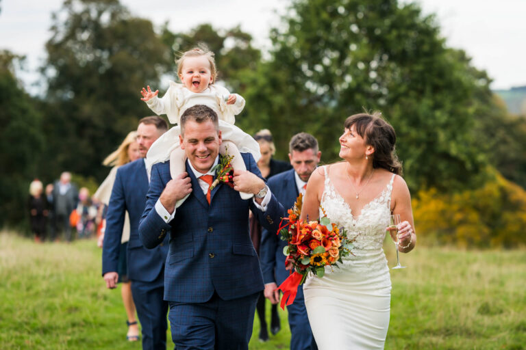 Smiling bride and groom walking outdoors cheerfully.