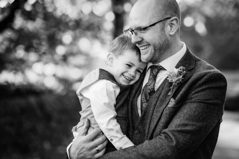 Man and boy smiling, embracing outdoors
