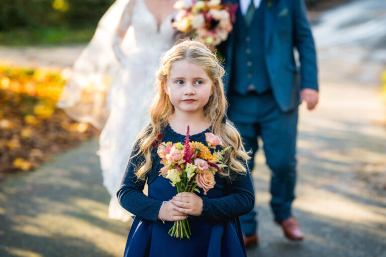 Young girl holds bouquet at wedding.