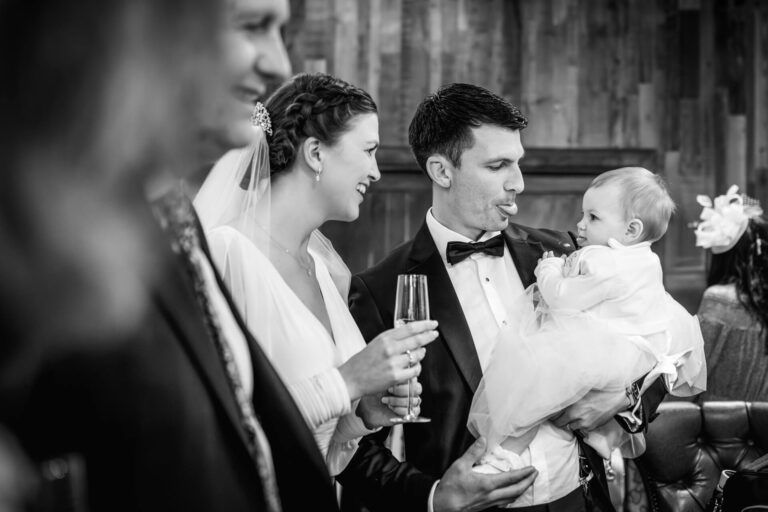 Wedding couple interacts with baby at reception.