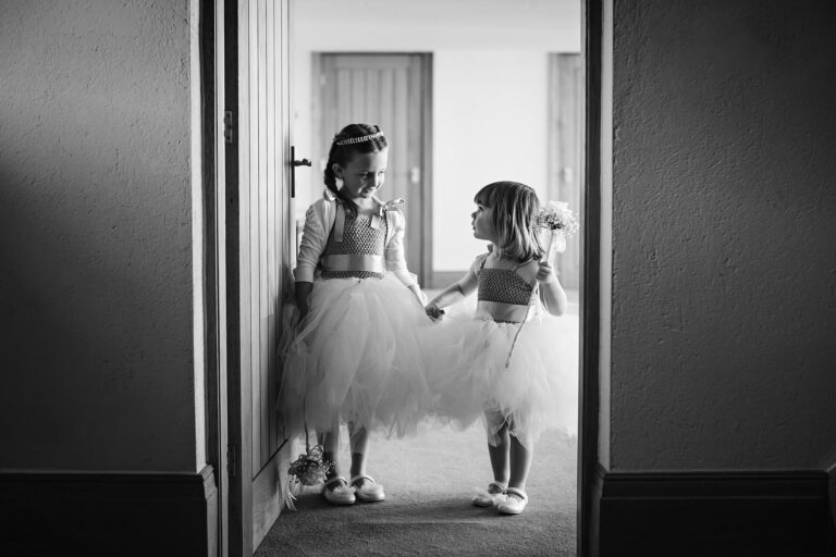 Two girls in dresses holding flowers, black and white.