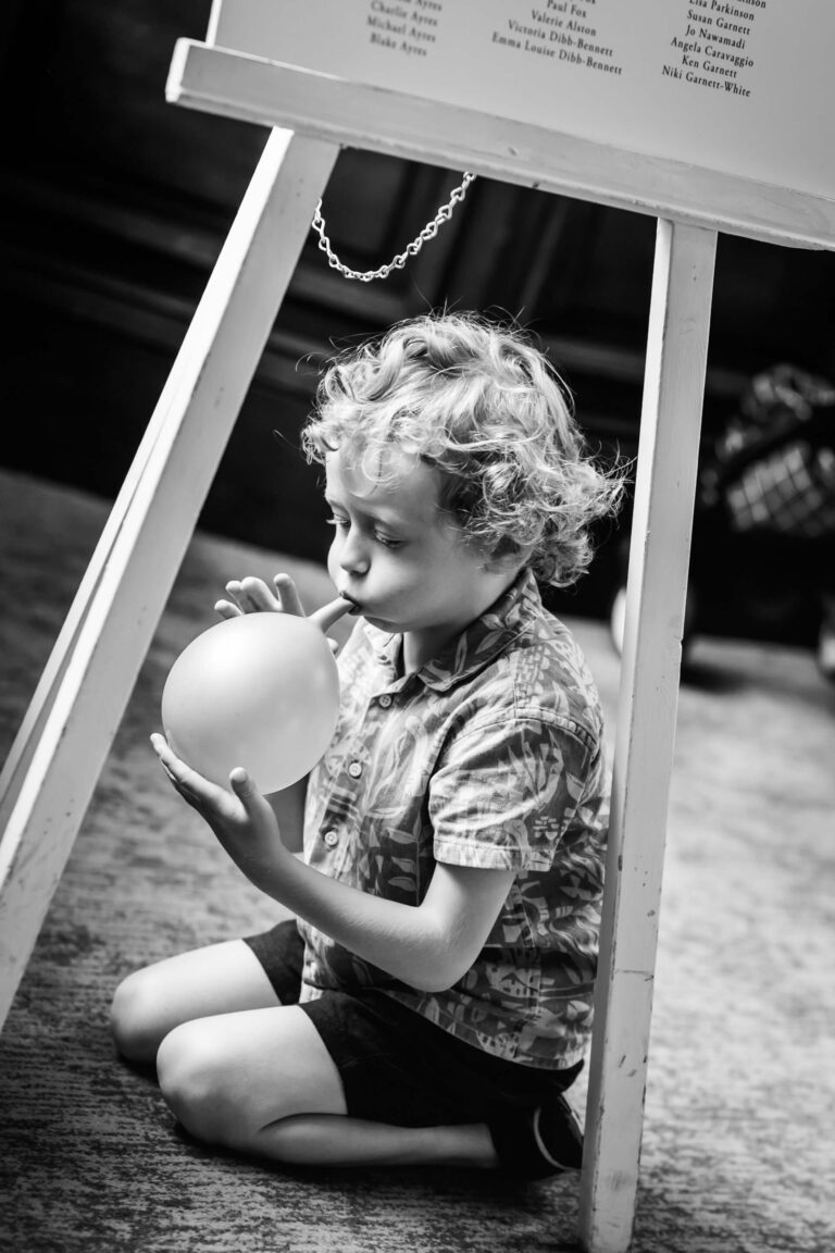 Young child blowing up a balloon indoors.