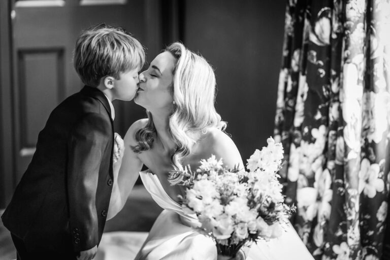 Bride kisses young boy at wedding
