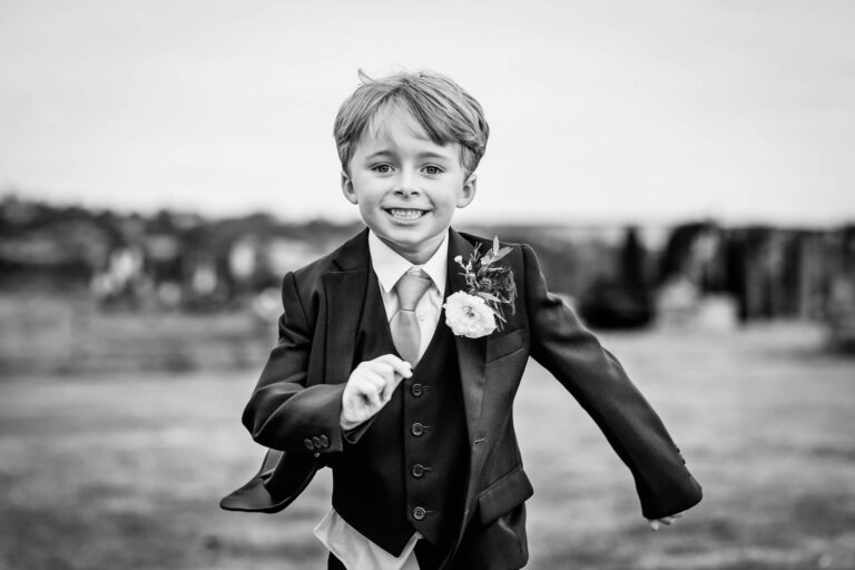 Smiling boy in suit running outdoors.