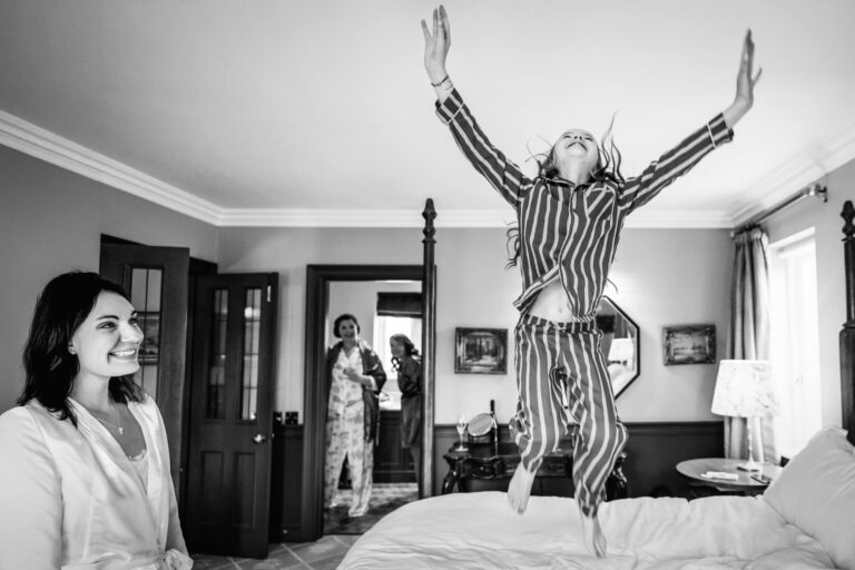 Child jumping on bed, laughing adults watching.