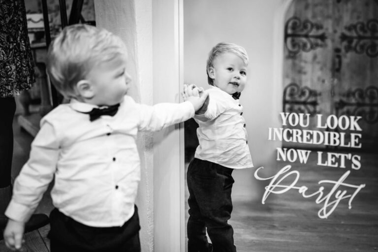 Child in bow tie admires mirror reflection