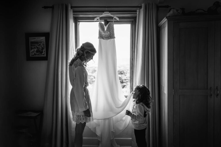 Bride and child with wedding dress in window.