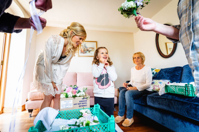 Bride preparing with family, flowers in living room