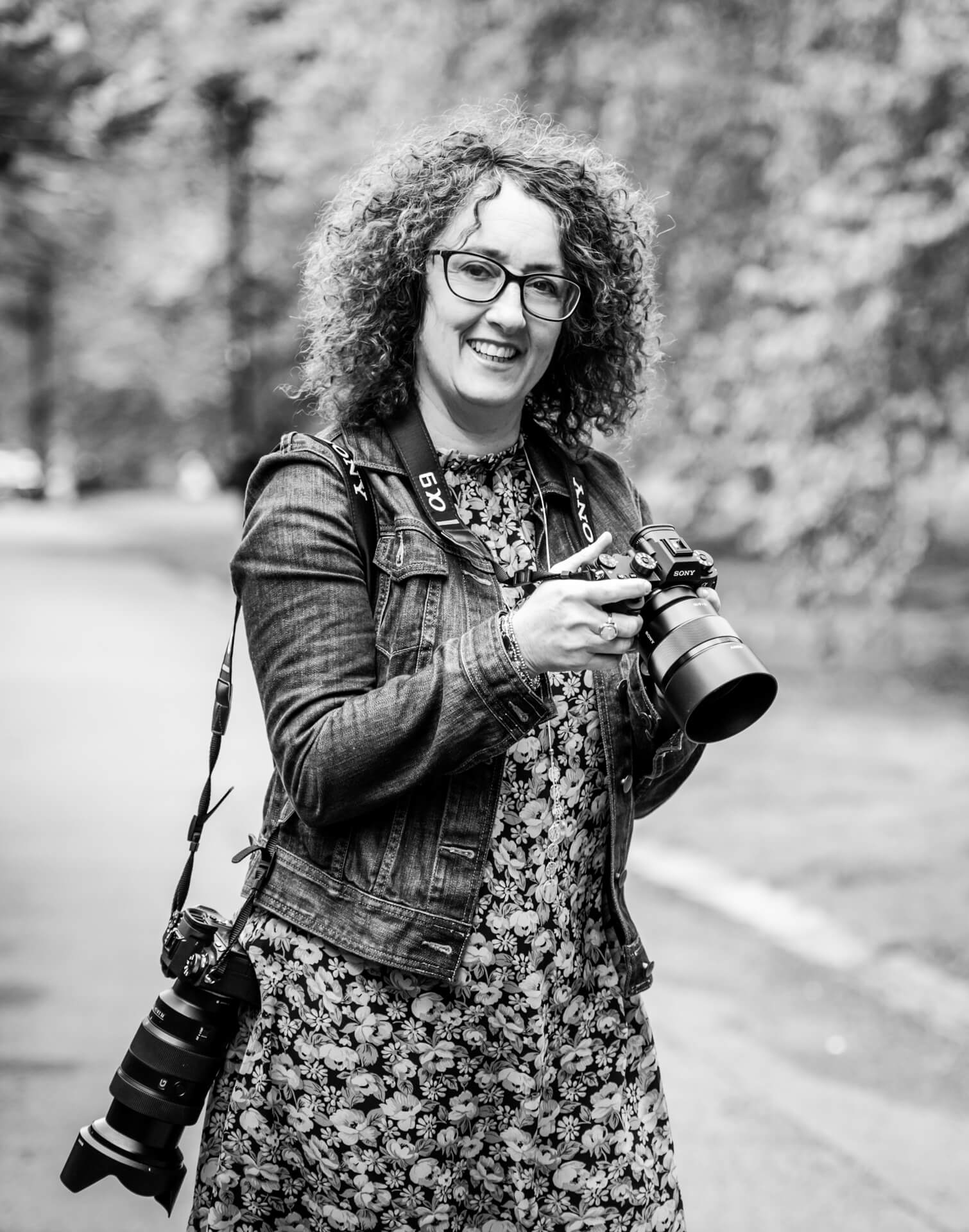 Smiling photographer holding camera in park